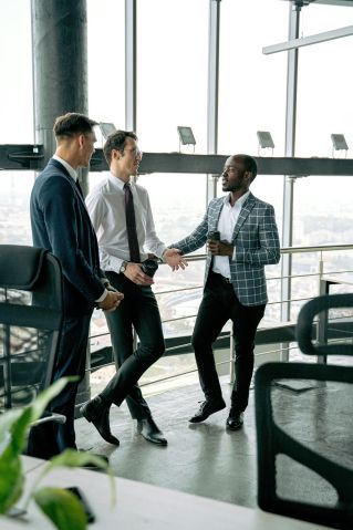 Businessmen having a conversation in a modern office setting, holding coffee cups.
