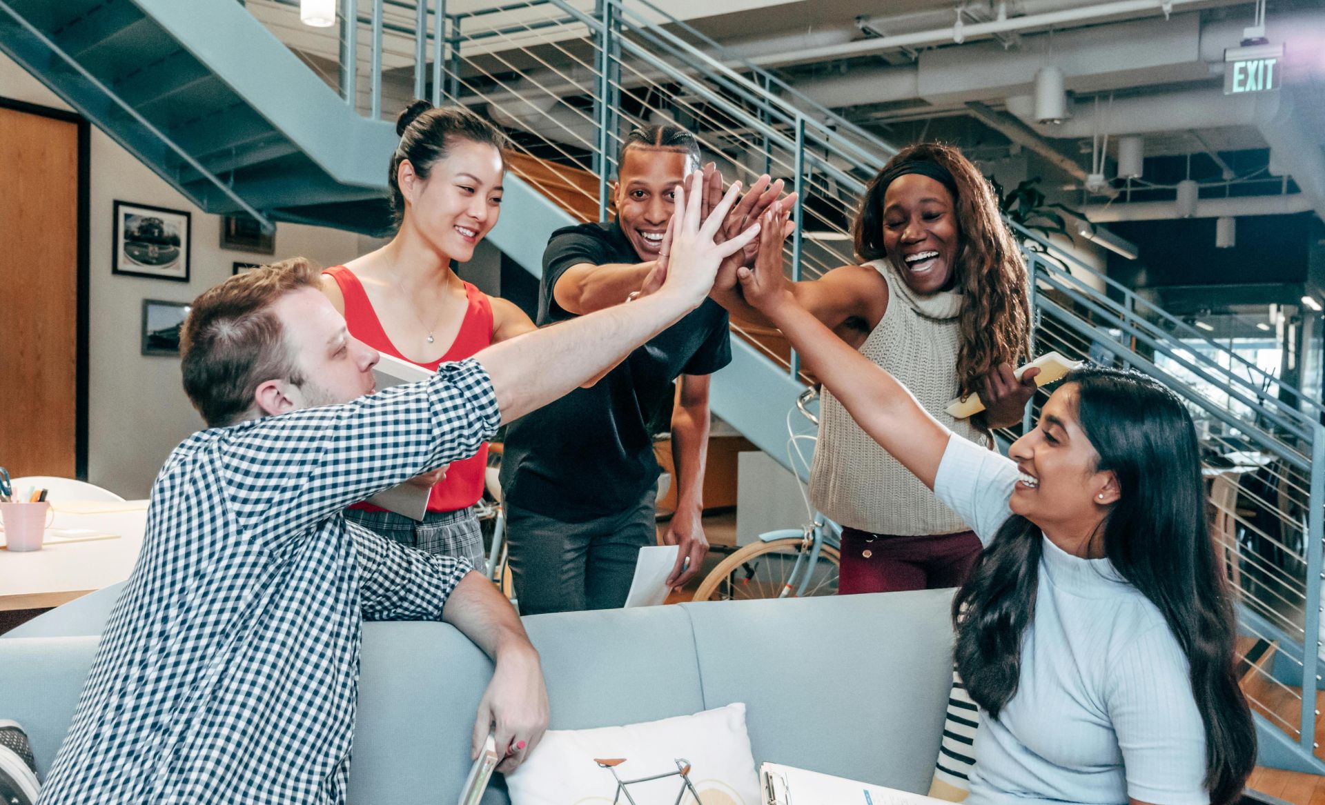A multicultural office team high-fiving and celebrating a successful collaboration.