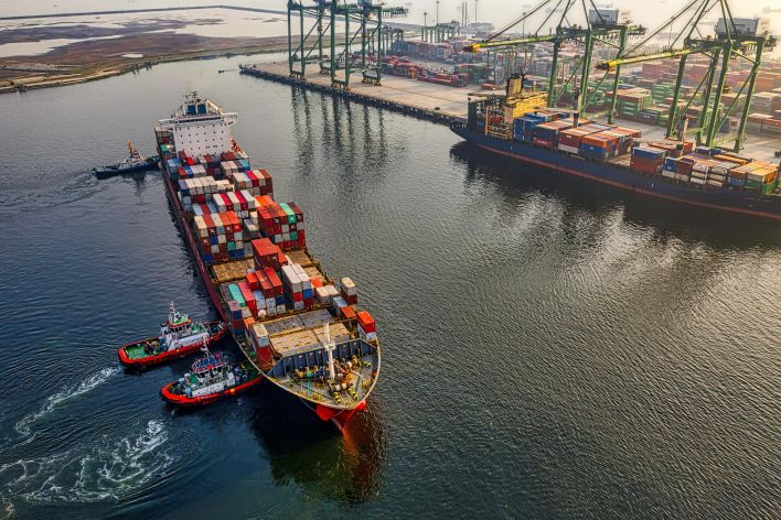 Aerial shot of cargo ships and cranes at North Jakarta port, showcasing global shipping and logistics.